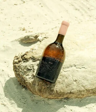 Château Galoupet Cru Classé Côtes de Provence Rosé bottle on cut vine wood pieces.