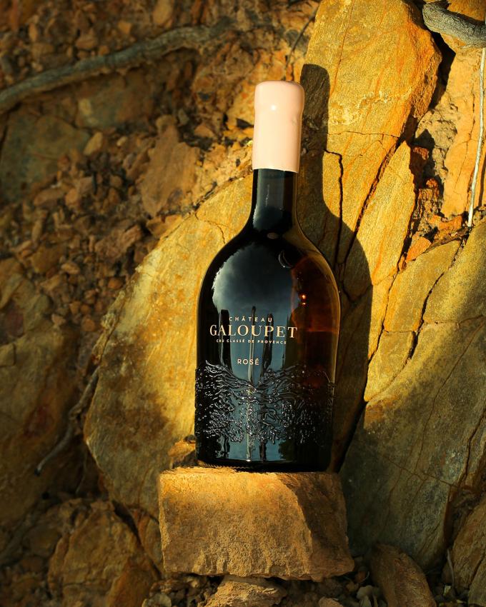 A bottle of Château Galoupet Cru Classé Rosé in front of the terroir