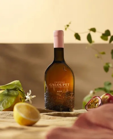 A bottle of Château Galoupet Cru Classé 2023 Rosé inbetween tasting notes, fruits and flowers in late afternoon. 