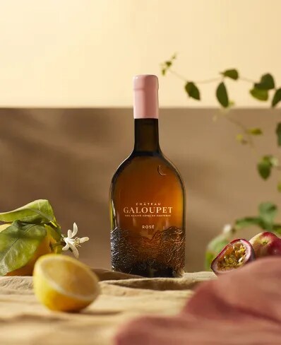 A bottle of Château Galoupet Cru Classé 2023 Rosé inbetween tasting notes, fruits and flowers in late afternoon. 