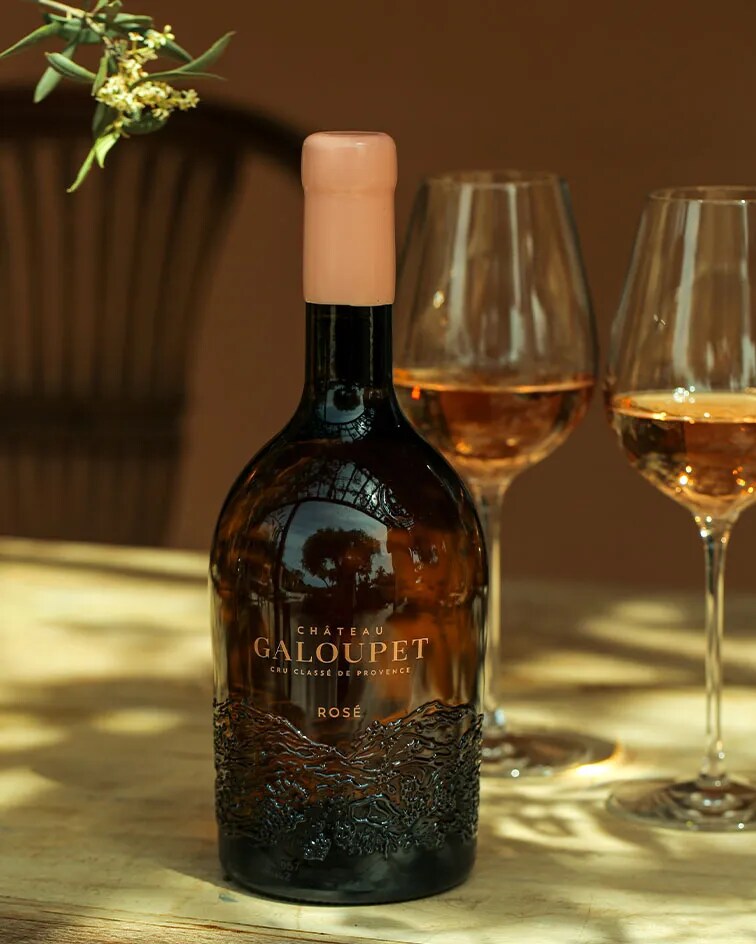 Bottle of Château Galoupet Cru Classé Côtes de Provence Rosé surrounded by fruits, vegetables and flowers.
